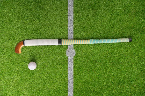 Hockey, ball and stick on green field, pitch and equipment against grass background. Sports equipment, top view and astroturf with in practice, training and sport.