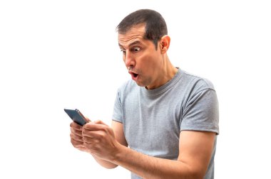 Latin bir adam beyaz arka planlı akıllı bir telefonla şaşırtıcı haberler alıyor.