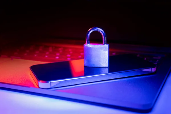 ブルーとレッドライトで照らされたラップトップと電話のパドロックのクローズアップ フィッシング サイバーセキュリティの危険性やランサムウェア攻撃 電子メールで暗号化されたプライバシー ストック写真
