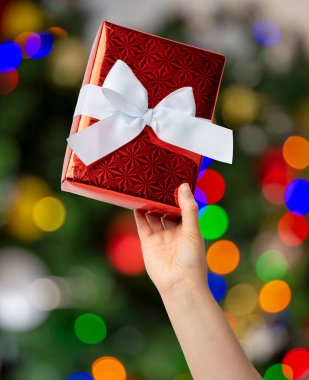 Kadının Noel hediyesini Noel ağacı arka planında kaldırdığı yakın plan..  