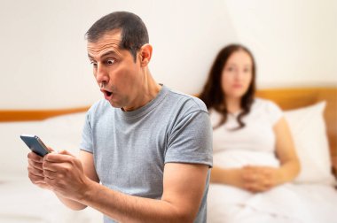 Latin bir adam beyaz arka planlı akıllı bir telefonla şaşırtıcı haberler alıyor.