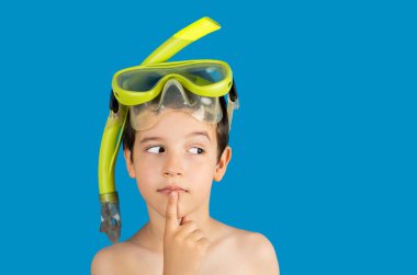 Pensive kid with snorkel mask tuba and snorkel looks away at copy space thinking isolated on a blue background, kid lips hold finger near mouth.Snorkeling, swimming, vacation concept. clipart