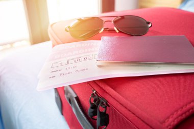 Pasaportlu ve güneş gözlüklü uçak biletleri evdeki yatak odasında.