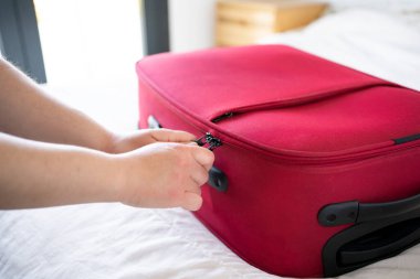 Kırmızı bavulunu kapatan genç bir kadının eli.