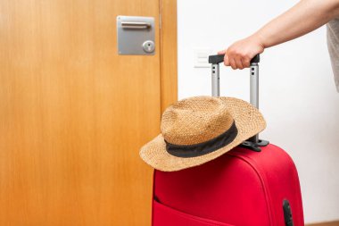 Kırmızı valiz ve hasır şapkalı kadın. Turizm konsepti.