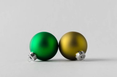 Yeşil ve sarı renkli Noel topları pürüzsüz gri arka planda.