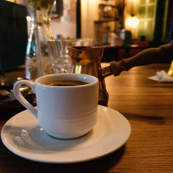 Arka planda kahve ısıtıcısı olan bir fincan Türk kahvesi.