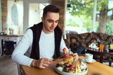 Genç, yetişkin, beyaz bir erkek restorandaki masada Burgher ve Fransız ateşiyle oturuyor. Patates cipsi tek başına yeniyor. Gerçek insanlar uzay kopyaları yapıyor.