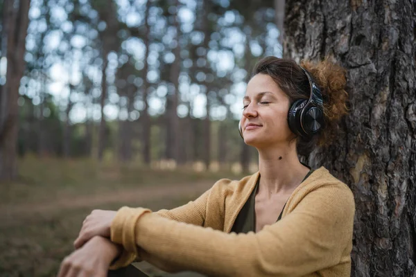 Genç Yetişkin Bir Kadın Parkta Ormanda Tek Başına Oturmuş Kulaklıklarıyla — Stok fotoğraf