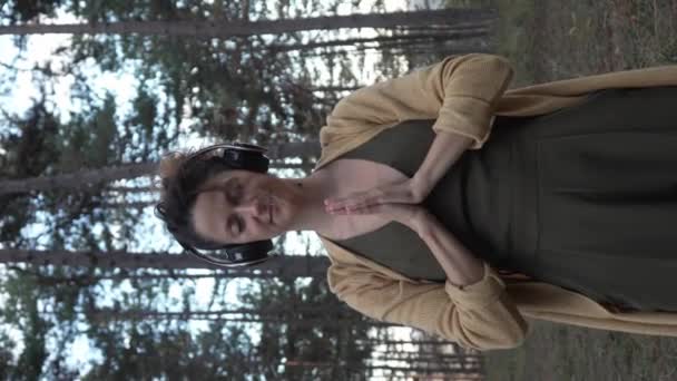 一个年轻的女性白人女性独自呆在公园或森林里 调整耳机准备冥想自我照顾自我表达练习精神情感平衡的概念 — 图库视频影像