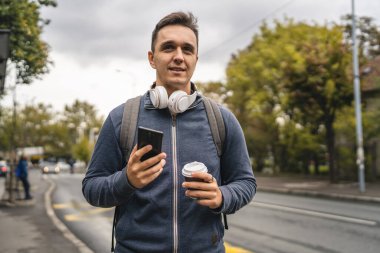 Genç, yetişkin, beyaz bir erkek, şehir dışında otobüs durağını bekliyor. Gündüz modern turist ya da öğrenci cep telefonuyla konuşuyor. Gerçek insanlar uzay kopyaları yapıyor.