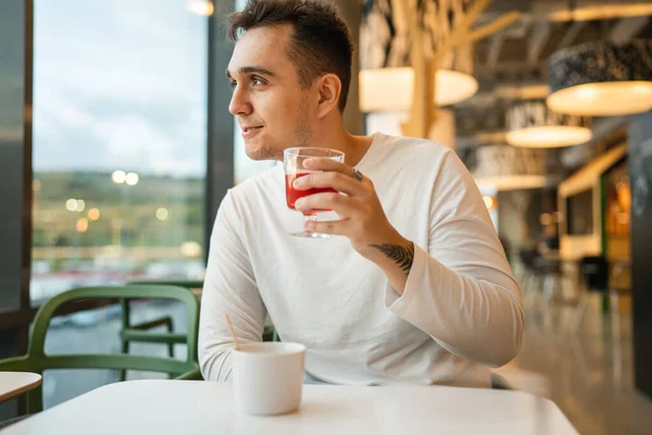 一人の若い大人の白人男性一人でカフェやレストランでテーブルに座るフルーツ輝く水のコピースペース本当の人々幸せな笑顔 — ストック写真