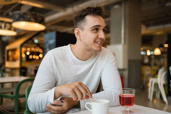 一人の若い大人の白人男性がカフェやレストランで一人でコーヒーを飲みながら側を見て座っている本物の人々は幸せな笑顔のスペースをコピー — ストック写真