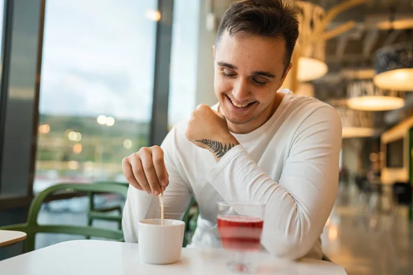一人の若い大人の白人男性がカフェやレストランで一人でコーヒーを飲みながら側を見て座っています本物の人々コピースペース — ストック写真
