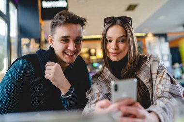 Kafkasyalı iki genç çift, kadın ve erkek arkadaş veya erkek arkadaş veya kız arkadaş selfie çekiyorlar ya da kafeteryada oturup eğlenirken ve romantizm yaparken görüntülü görüşme yapıyorlar.