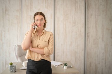 Ofisinin önünde duran beyaz kadın iş kadını yönetici ya da sekreter fotokopi odası mutlu bir gülümseme cep telefonuyla arama yapıyor.