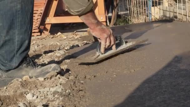 用铲子把水泥混凝土的顶部磨成所需的平整度的建筑工人用手铲子铺平路面 — 图库视频影像