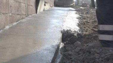 Bilinmeyen adamın orta kısmı kürek tutuyor inşaat alanındaki el arabasından beton döşeme kaldırımlarına beton döküyor.
