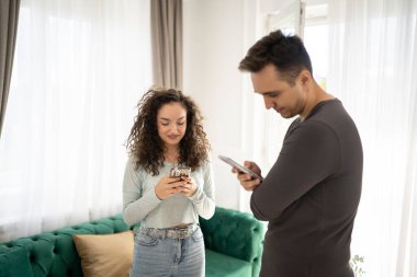 Genç yetişkin kadın ve erkek ve kadın erkek ve kız arkadaş, evde ayrı mesajlaşırken ya da internette internette gezinirken akıllı telefon kullanıyor.