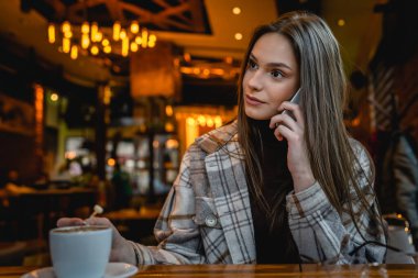 Yetişkin bir kadın Kafe 'de tek başına oturmuş cep telefonuyla fotokopi çekiyor.