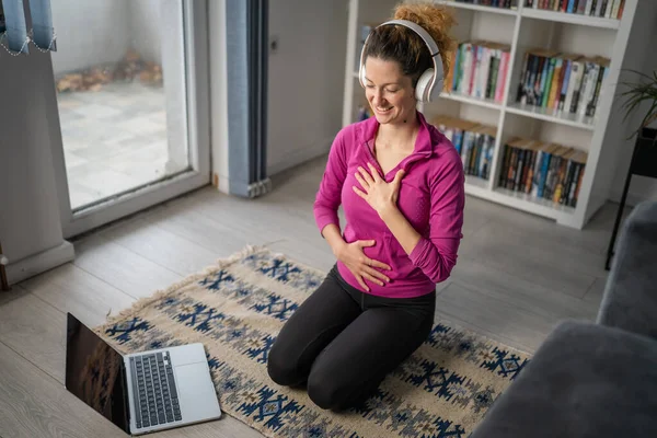 オンラインガイド付き瞑想のためのヘッドフォンとラップトップコンピュータを使用して1人の女性大人の白人女性千年紀自宅で床の上に目を閉じてマインドフルネスヨガを練習人々はスペースをコピー — ストック写真