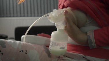Bilinmeyen beyaz kadının karnını kapatın ve bebeği için bebek şişesi ve göğüs pompası kullanın. Geceleri süt pompalayın. Ebeveynlik ve annelik kavramı.
