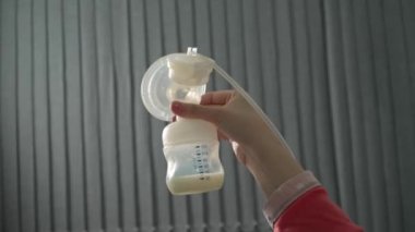 Bilinmeyen beyaz kadının karnını kapatın ve bebeği için bebek şişesi ve göğüs pompası kullanın. Geceleri süt pompalayın. Ebeveynlik ve annelik kavramı.