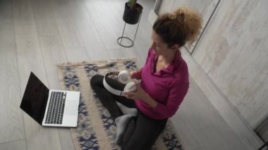 Yetişkin bir beyaz kadın milenyum kulaklığı ve dizüstü bilgisayarı kullanarak online meditasyon yapan evde gözleri kapalı yoga yapan gerçek insanlar.