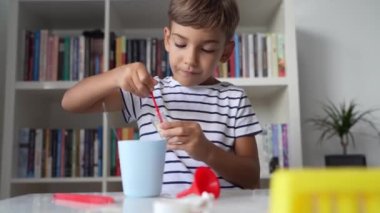 Anaokulundan bir çocuk evde oturmuş bilim deneyi oyuncaklarıyla oynuyor kameraya bakıyor çocukluğunda gülümseyen konsepte bakıyor.