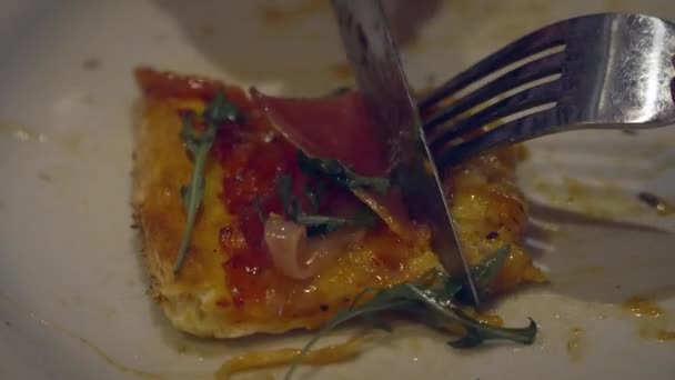 用叉子和刀叉在黑暗的餐馆里吃着盘子里切的一块披萨 — 图库视频影像