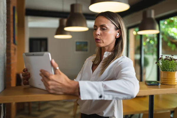 1人の女性大人成熟した白人女性起業家マネージャーは 自宅や職場でテーブルの屋内に立っている間 デジタルタブレットを使用して作業白いシャツコピースペースを身に着けている — ストック写真