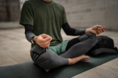Bir adam rehberli meditasyon yapıyor çevrimiçi yoga kişisel bakım konsepti açık havada, göbek kısmını kapatıyor.
