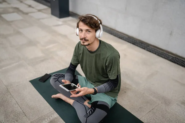 Yetişkin Bir Erkek Yoga Meditasyona Hazırlanırken Kulaklıklarla Dışarıda Otururken Dijital — Stok fotoğraf