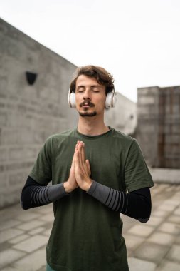 Genç, yetişkin, beyaz erkek, bıyıklı, modern insan portresi. Kulaklık takıyor. Kameraya bakıyor.