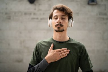 Genç, yetişkin, beyaz erkek, bıyıklı modern insan portresi. Kulaklık takıyor. Kameraya bakıyor.