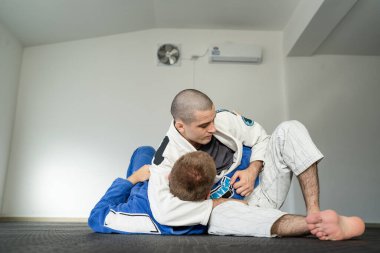 Brezilya jiu jitsu kesa yan kontrol eğitimi alan iki sporcu akademide kimono giyim üniformasıyla BJJ 'i tutuyor.