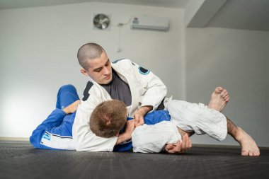 Brezilya jiu jitsu kesa yan kontrol eğitimi alan iki sporcu akademide kimono giyim üniformasıyla BJJ 'i tutuyor.