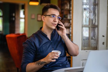 Genç, beyaz bir erkek, evde ya da kafede oturup dizüstü bilgisayarda tek başına gülümsüyor serbest gülüyor. Gerçek insanlar cep telefonu konuşmaları yaparak mekanı kopyalıyor.