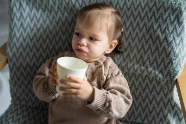 Küçük beyaz bir kız çocuğu plastik bardakta su tutuyor. Fotokopi alanı kadar.