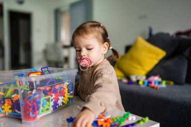 Bir çocuk, küçük beyaz kız, meme ucu emziği olan, evde tek başına oynayan, çocukluk dönemi konsepti fotokopi alanı.