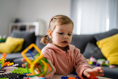 Bir çocuk, küçük beyaz bir kız çocuğu evde masada tek başına oynuyor çocukluk konsepti fotokopi alanı.