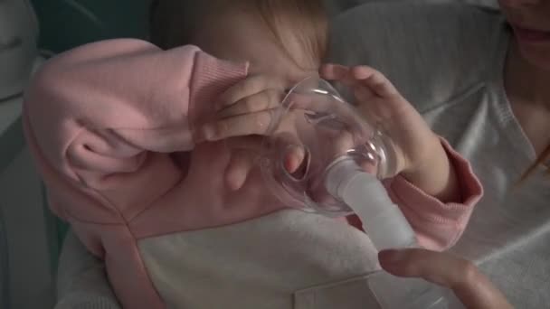 1人の幼児の女の子小さいCaucasian娘座っています椅子に彼女の母親拒否使用Nebulizer自宅で子供用蒸気スチーム吸入マスク吸入医療処置 — ストック動画