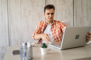 One caucasian man sitting at office at work working on laptop computer in day young freelance or entrepreneur businessman online business copy space young adult finishing or beginning confident think