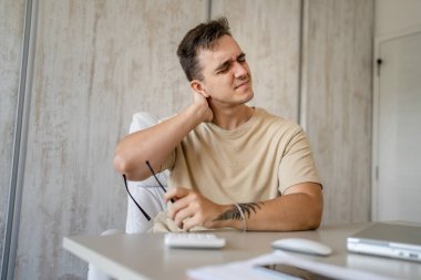 One man freelancer stretch in the office at work sitting in chair at desk using laptop computer having pain sore back suffering from neck ache overwork and exhaustion concept copy space