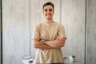 One man adult caucasian male standing in front of table desk at work in the office or work from home wear shirt looking confident casual happy smile copy space real people freelance work