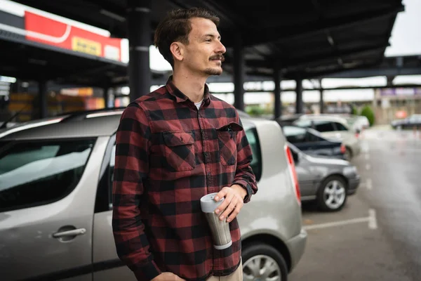 駐車場で車のそばに立っている大人の白人男性は 仕事中にコーヒーを飲みながら待っています — ストック写真