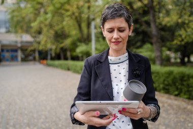 Üst düzey yetişkin bir kadın dijital tablet kullanıyor. Uzaktan kumandalı internet üzerinde çalışıyor. Posta gönderiyor ya da okuyor.