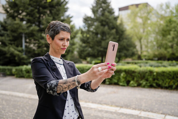 One woman mature or senior caucasian female standing outdoor alone taking selfie photos or making a video call happy smile confident real people modern lifestyle copy space