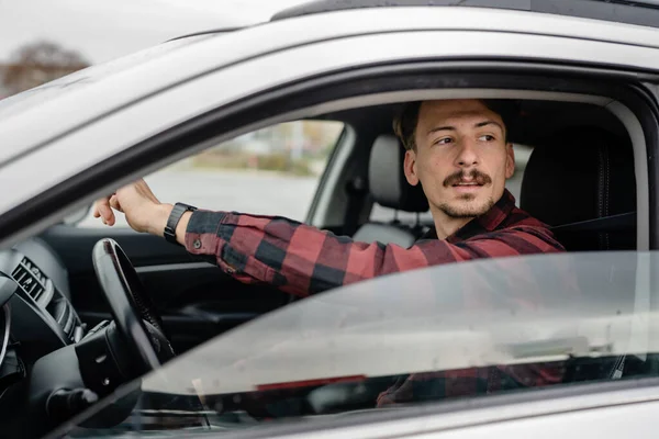 one man caucasian male with brown hair and mustaches sitting in a car adult driver wear shirt while driving automobile travel transport concept real people copy space