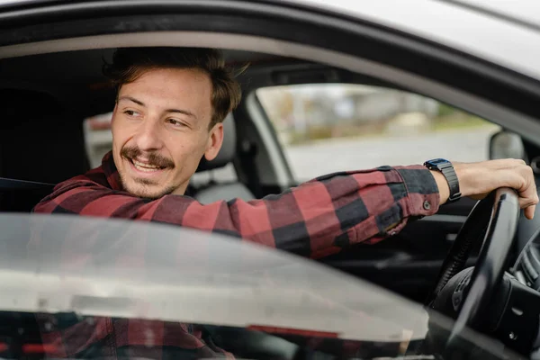 one man caucasian male with brown hair and mustaches sitting in a car adult driver wear shirt while driving automobile travel transport concept real people copy space happy smile